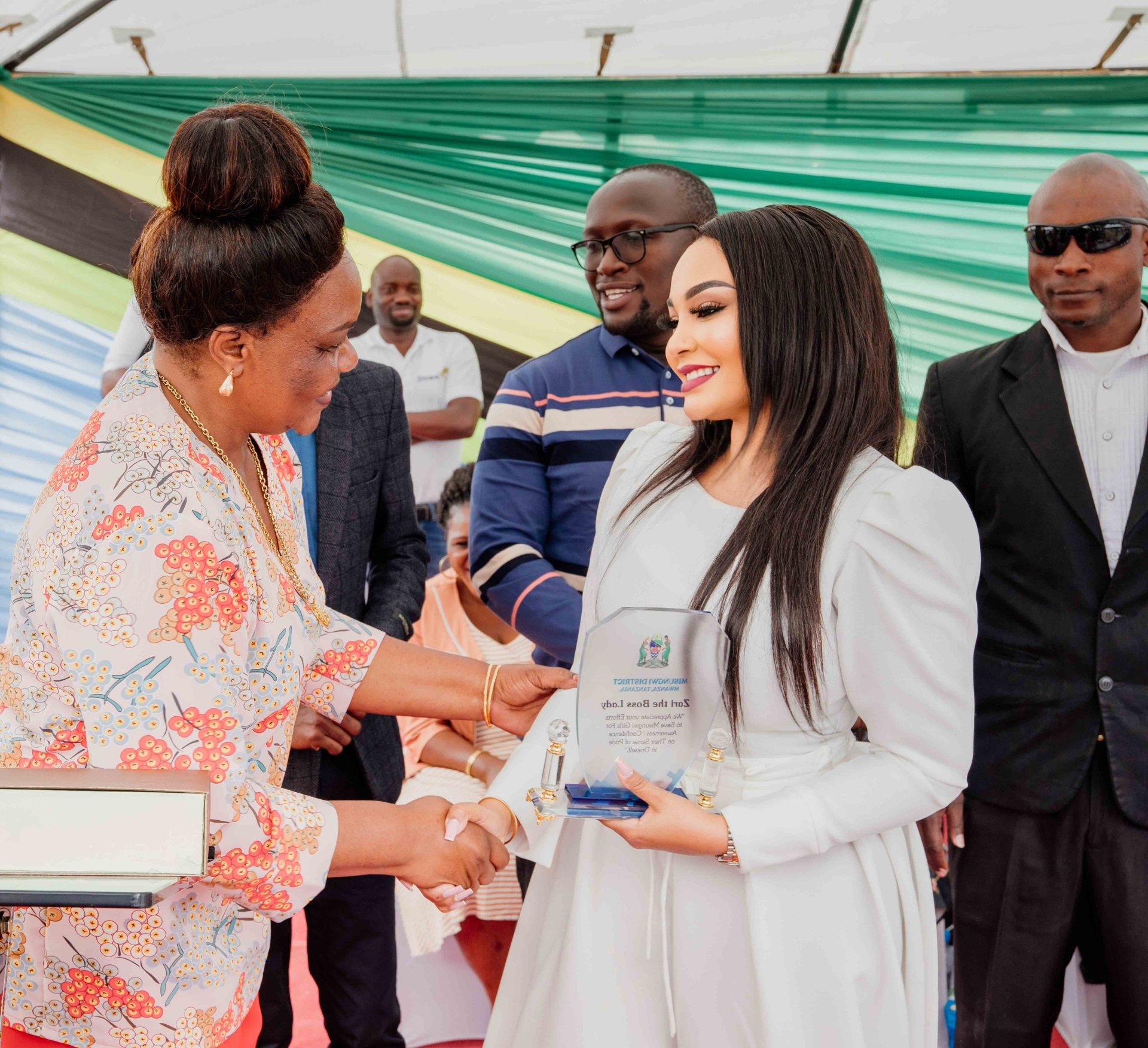 Zari Hassan receiving a plaque of appreciation from district officials