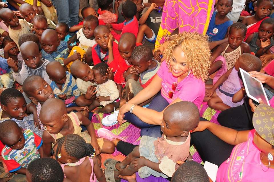 Zari Hassan sitting among a large group of children during a community visit