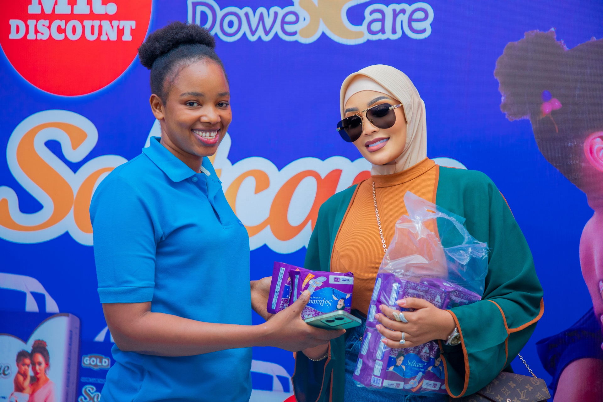 Zari Hassan handing sanitary care packages to a young woman at a distribution event