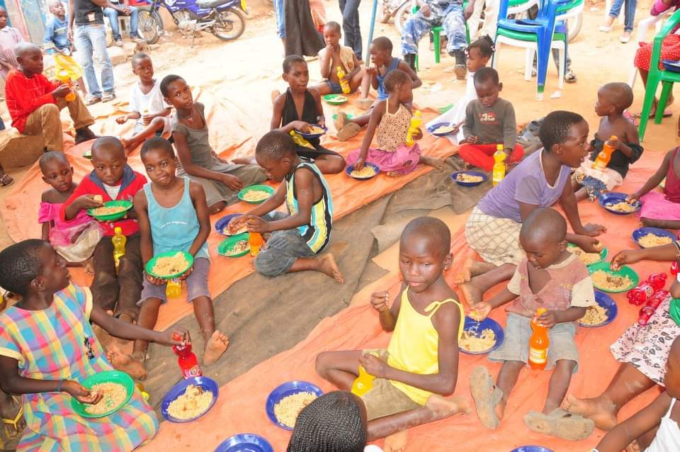 Children sitting together enjoying plates of food and drinks at a community meal