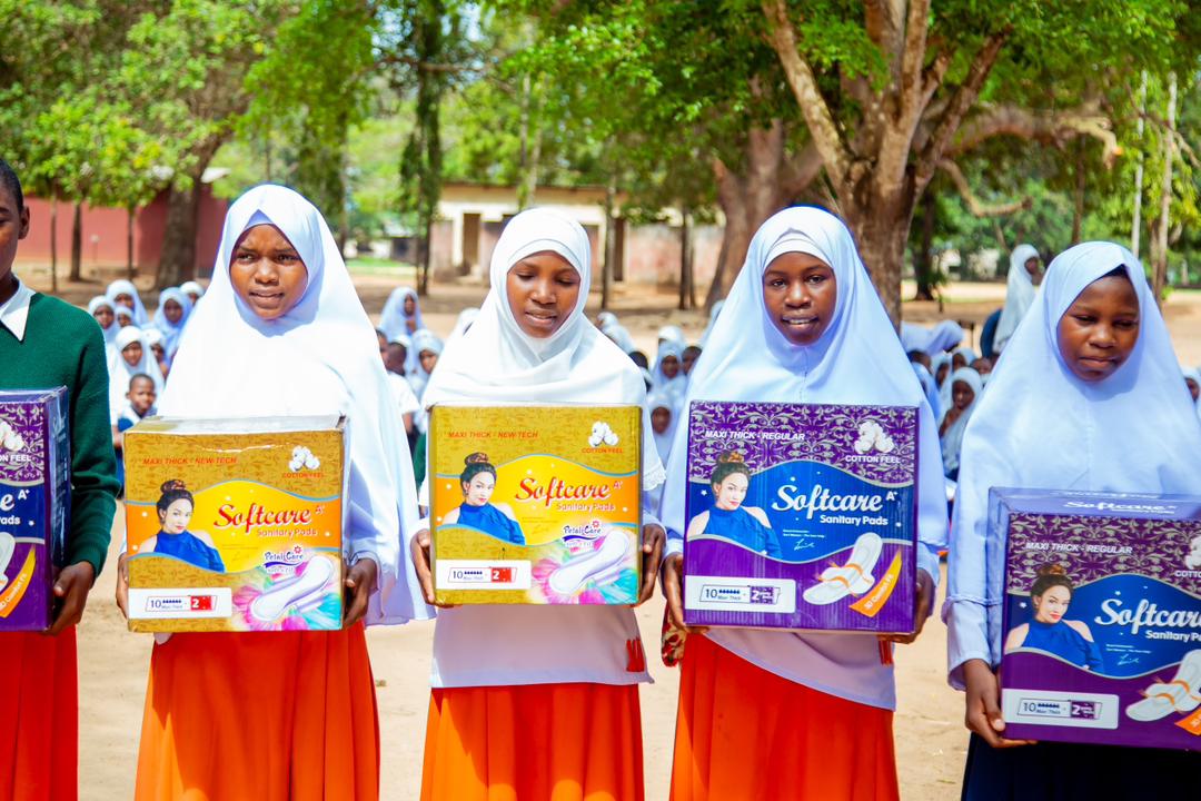 Schoolgirls holding boxes of Softcare sanitary pads received during a foundation visit