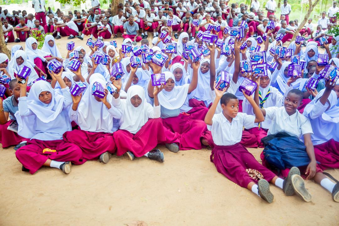 A large group of schoolchildren proudly holding sanitary care packages received from the foundation
